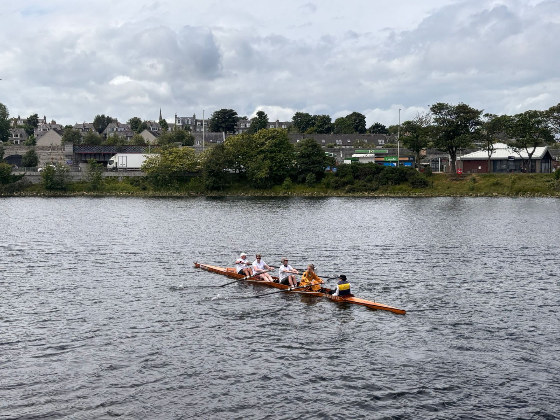 Imrandd rowing team on a river in an orange shell